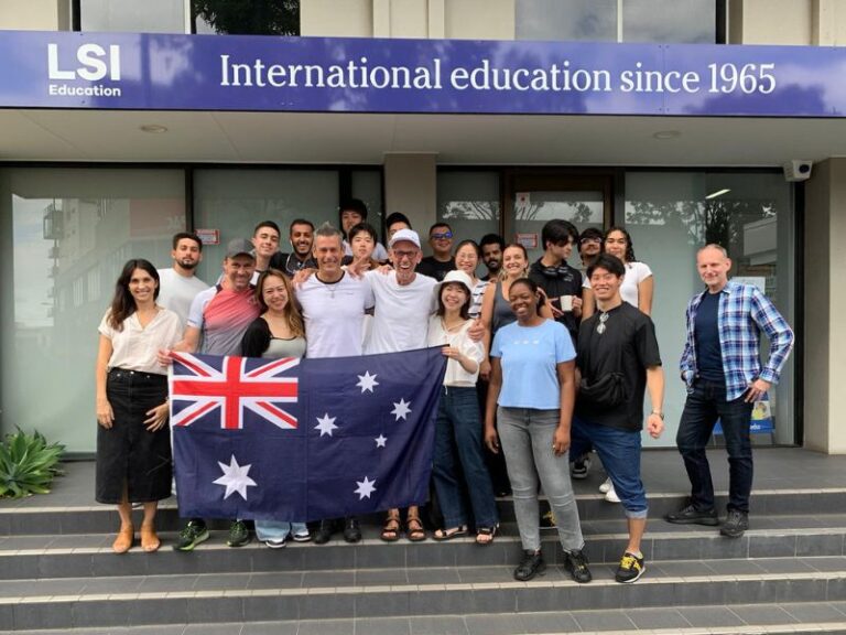 GradGroupWithFlagInFrontOfSchool